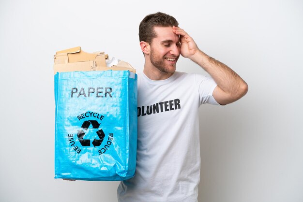 Hombre caucásico joven sosteniendo una bolsa de reciclaje llena de papel para reciclar aislado sobre fondo blanco sonriendo mucho