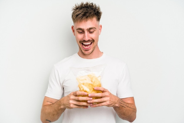 Hombre caucásico joven sosteniendo patatas fritas aislado sobre fondo blanco.