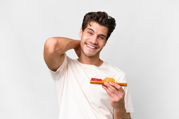 Foto hombre caucásico joven sosteniendo sashimi sobre fondo blanco aislado riendo