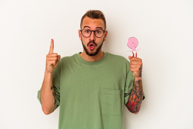 Hombre caucásico joven con tatuajes con piruleta aislado sobre fondo blanco con una gran idea, concepto de creatividad.