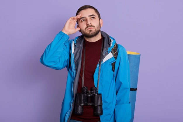 Hombre caucásico joven viajero mirando hacia arriba con expresión facial dudosa