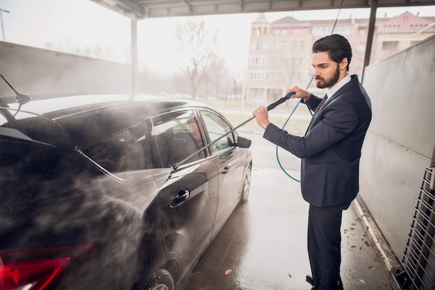 Hombre caucásico lavando su coche en lavado de autos.