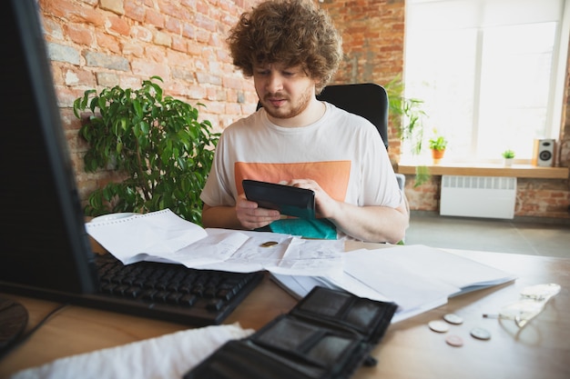 Hombre caucásico malestar y desesperación viendo informes financieros y económicos