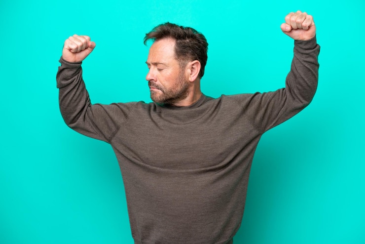 Foto hombre caucásico de mediana edad aislado de fondo azul haciendo un gesto fuerte