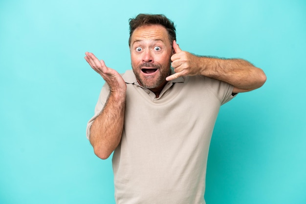 Hombre caucásico de mediana edad aislado de fondo azul haciendo gestos telefónicos y dudando