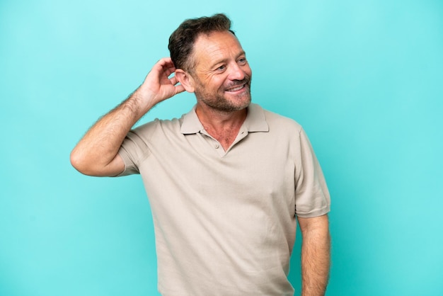 Hombre caucásico de mediana edad aislado de fondo azul que tiene dudas