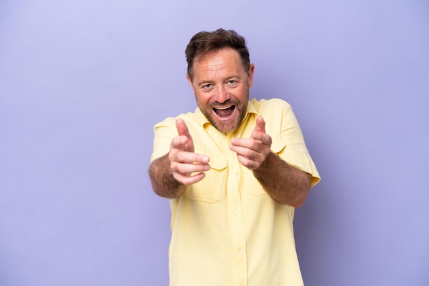 Hombre caucásico de mediana edad aislado de fondo morado apuntando al frente y sonriendo