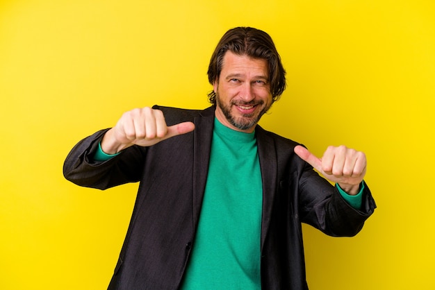 Hombre caucásico de mediana edad aislado en la pared amarilla levantando ambos pulgares, sonriente y confiado.