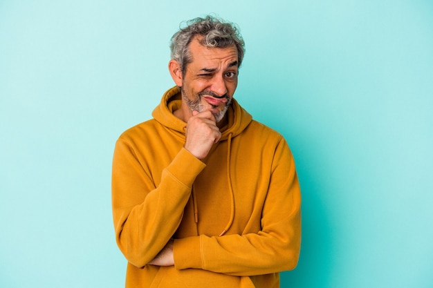 Hombre caucásico de mediana edad aislado sobre fondo azul pensando y mirando hacia arriba, siendo reflexivo, contemplando, teniendo una fantasía.