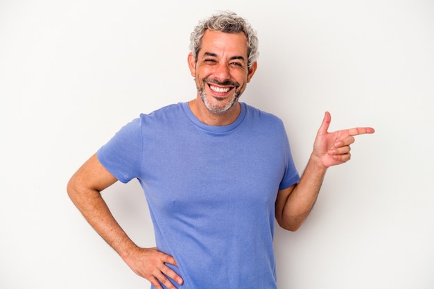 Hombre caucásico de mediana edad aislado sobre fondo blanco sonriendo alegremente apuntando con el dedo índice.
