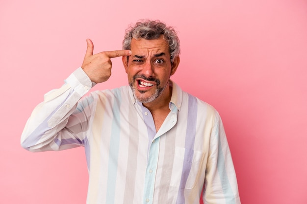 Hombre caucásico de mediana edad aislado sobre fondo rosa mostrando un gesto de decepción con el dedo índice.