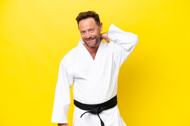 Foto hombre caucásico de mediana edad haciendo karate aislado sobre fondo amarillo riendo