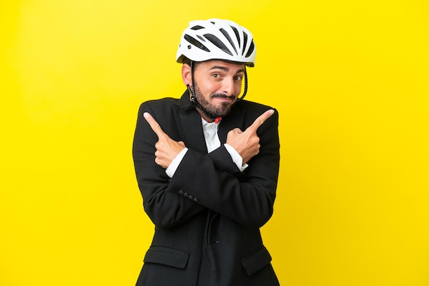 Hombre caucásico de negocios con un casco de bicicleta aislado en un fondo amarillo que apunta a los laterales que tienen dudas