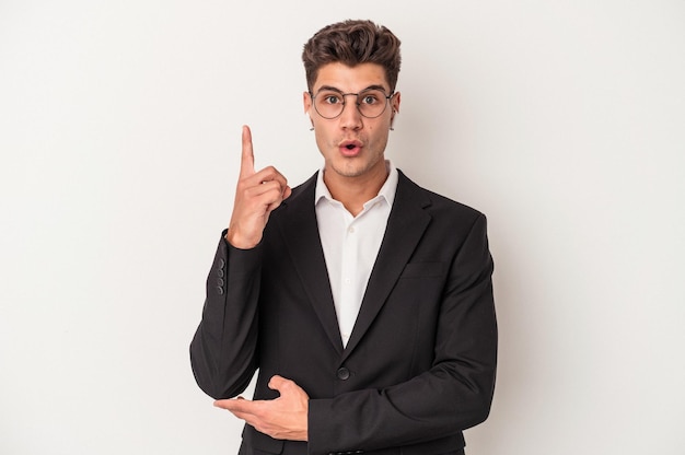 Hombre caucásico de negocios joven con auriculares aislados en fondo blanco que tiene una gran idea, concepto de creatividad.