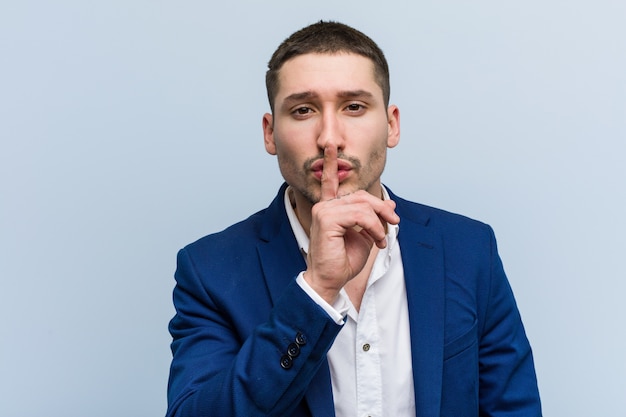 Hombre caucásico de negocios joven que guarda un secreto o que pide silencio.