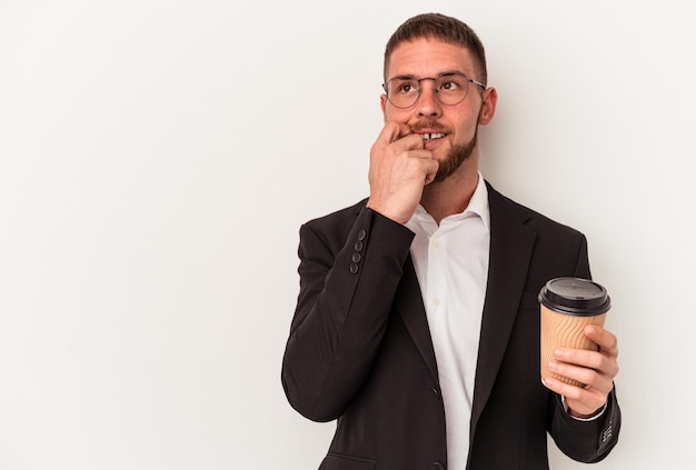 Hombre caucásico de negocios joven sosteniendo café para llevar aislado sobre fondo blanco relajado pensando en algo mirando un espacio de copia.