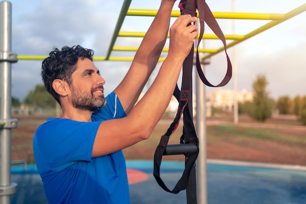 Hombre caucásico preparando un gran entrenamiento TRX al aire libre en el parque Estilo de vida saludable