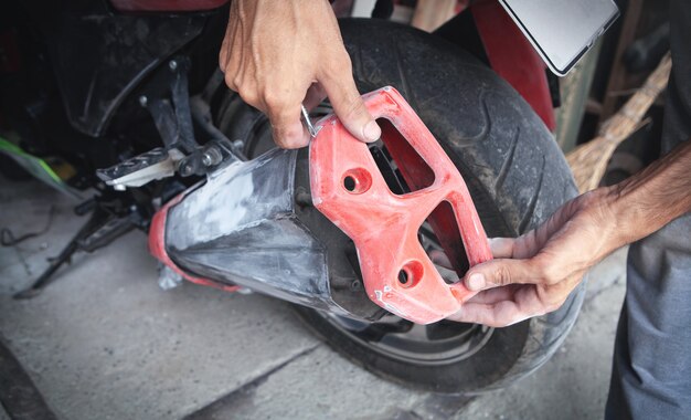 Hombre caucásico reparando su motocicleta en el garaje.