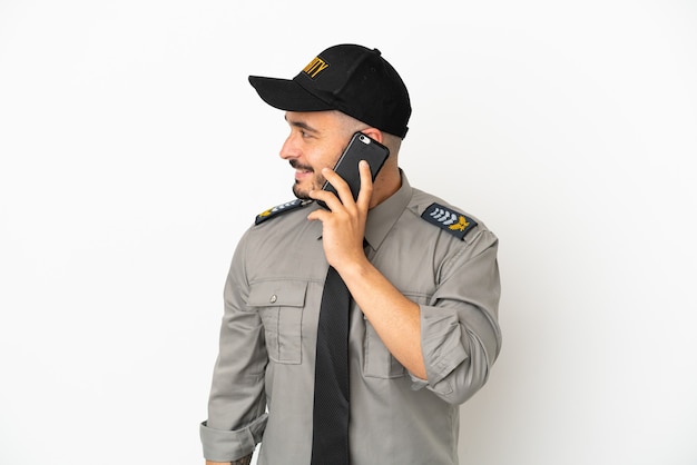 Hombre caucásico de seguridad joven aislado sobre fondo blanco manteniendo una conversación con el teléfono móvil con alguien