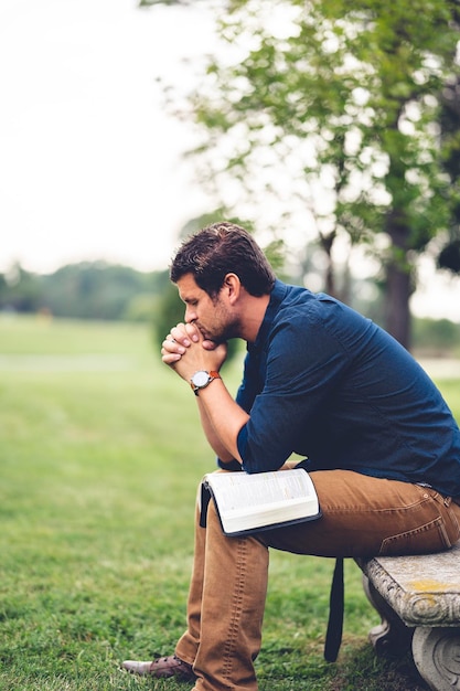 Foto hombre caucásico sentado y orando en el parque