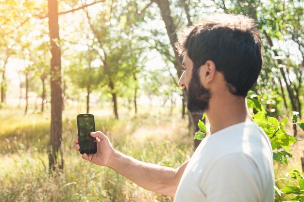 Hombre caucásico con smartphone en la naturaleza.