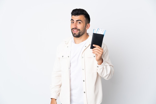 Hombre caucásico sobre fondo blanco aislado feliz de vacaciones con pasaporte y billetes de avión