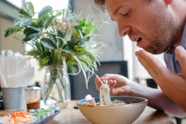 El hombre caucásico se sorprende con lo picante que es la sopa de fideos