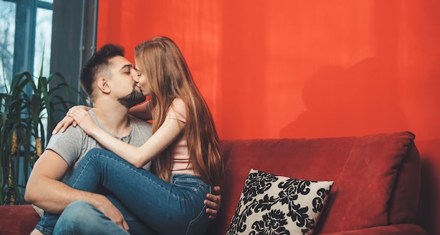 Hombre caucásico sosteniendo a su mujer de jengibre en las piernas y besándola celebrando juntos el día de San Valentín