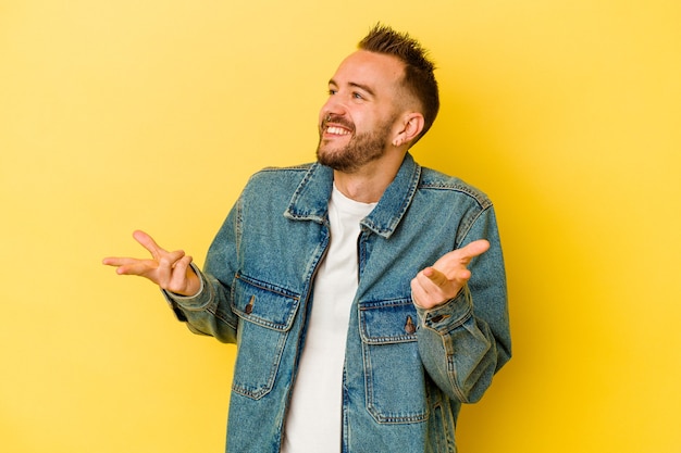 Hombre caucásico tatuado joven aislado sobre fondo amarillo alegre riendo mucho. Concepto de felicidad.