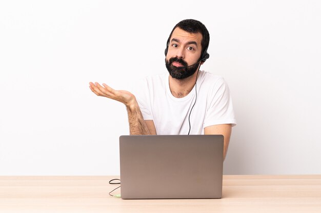 Hombre caucásico de telemarketing que trabaja con un auricular y con una computadora portátil que tiene dudas.