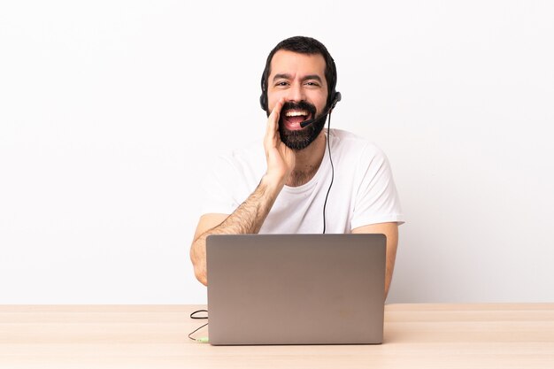 Foto hombre caucásico de telemarketing que trabaja con un auricular y con un portátil gritando con la boca abierta.