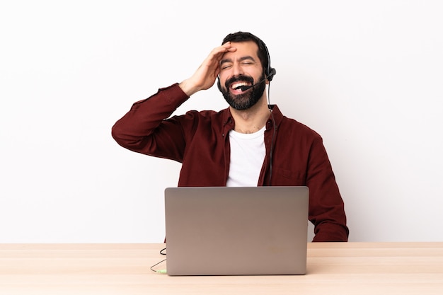 Hombre caucásico de telemarketing que trabaja con un auricular y con un portátil sonriendo mucho.