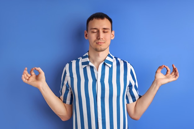 Hombre caucásico tranquilo meditando con los ojos cerrados, mantener la calma, en pose de yoga.