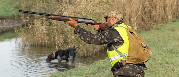 Hombre cazador camuflado con un arma durante la caza en busca de aves silvestres o caza. Temporada de caza de otoño.