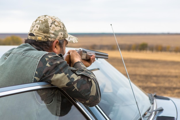 Hombre cazador camuflado con un arma durante la caza en busca de aves silvestres o caza