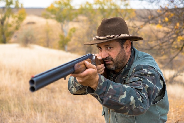 Hombre cazador camuflado con un arma durante la caza en busca de aves silvestres o caza