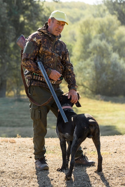 Hombre cazador camuflado con un arma durante la caza en busca de aves silvestres o juego Temporada de caza de otoño