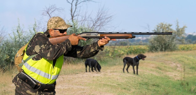 Hombre cazador camuflado con un arma durante la caza en busca de aves silvestres o juego Temporada de caza de otoño