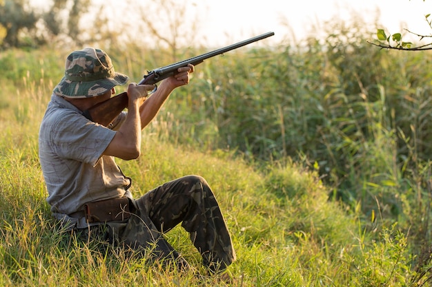 Hombre cazador en camuflaje con una pistola durante la caza en busca de aves silvestres o caza. Temporada de caza de otoño.