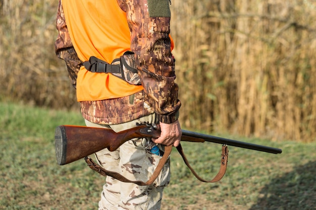 Hombre cazador en camuflaje con una pistola durante la caza en busca de aves silvestres o caza. Temporada de caza de otoño.