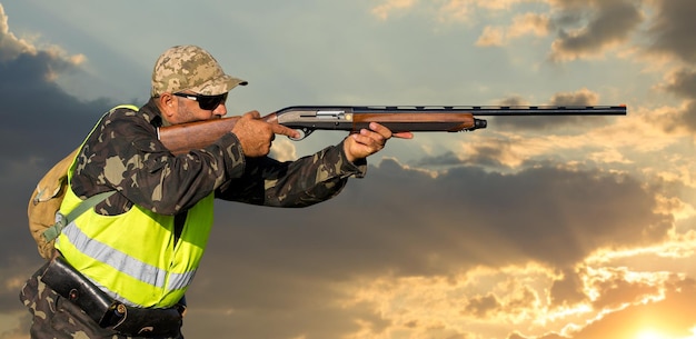 Hombre cazador en camuflaje con una pistola durante la caza en busca de aves silvestres o caza