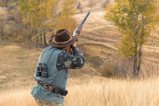 Hombre cazador en camuflaje con una pistola durante la caza en busca de aves silvestres o caza