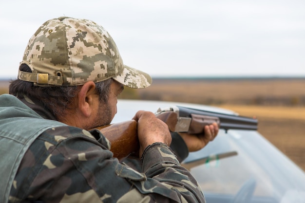 Hombre cazador en camuflaje con una pistola durante la caza en busca de aves silvestres o caza