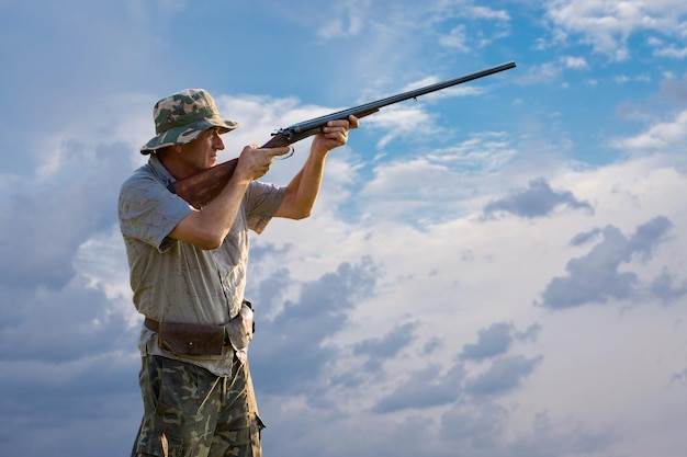 Hombre cazador en camuflaje con una pistola durante la caza en busca de aves silvestres o caza