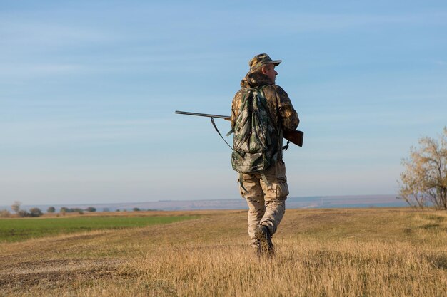 Hombre cazador en camuflaje con una pistola durante la caza en busca de aves silvestres o caza