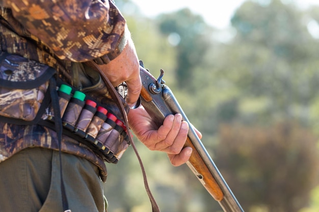 Hombre cazador en camuflaje con una pistola durante la caza en busca de aves silvestres o caza