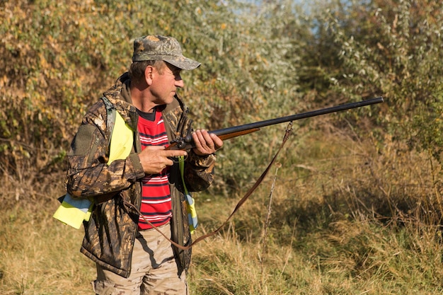 Hombre cazador en camuflaje con una pistola durante la caza en busca de aves silvestres o caza