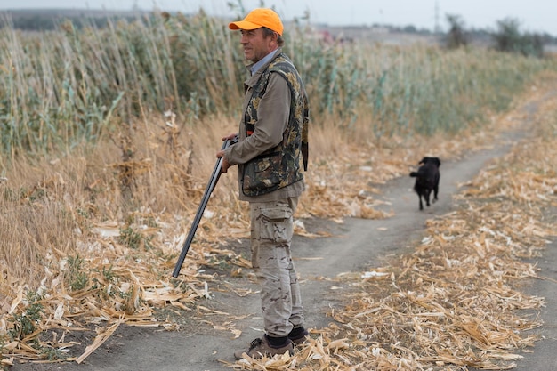 Hombre cazador en camuflaje con una pistola durante la caza en busca de aves silvestres o caza