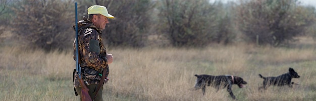 Hombre cazador en camuflaje con una pistola durante la caza en busca de aves silvestres o caza