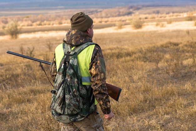 Hombre cazador en camuflaje con una pistola durante la caza en busca de aves silvestres o caza